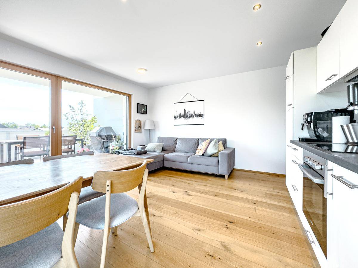Heller Wohn-Essbereich mit Holzboden, gemütlichem Sofa und Zugang zur Terrasse.
