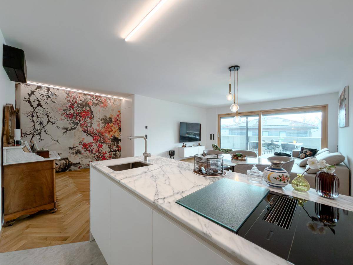 Offener Wohnbereich mit moderner Küche, Marmorinsel, dekorativer Wand und Zugang zur Terrasse.