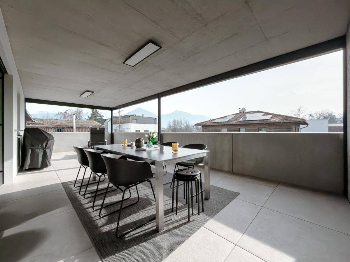 Geräumige Terrasse mit Esstisch, modernen Möbeln und weitem Blick auf die umliegende Berglandschaft.