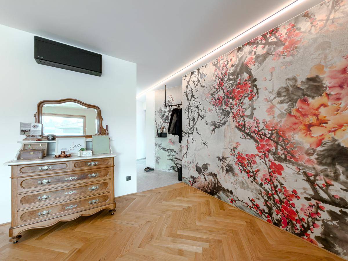 Übergangsbereich mit dekorativer Wandtapete, antiker Kommode und elegantem Fischgrätparkett.
