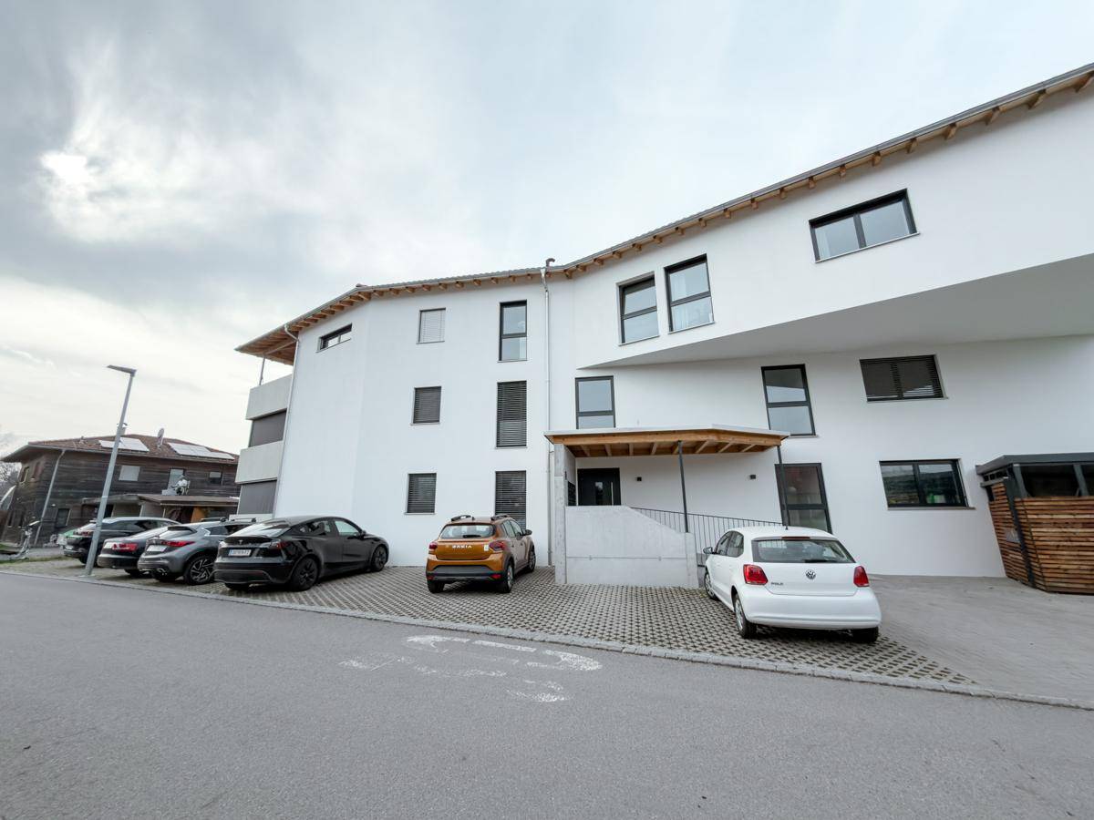 Moderne Architektur des Wohngebäudes mit klarer Linienführung und ausreichend Parkmöglichkeiten.