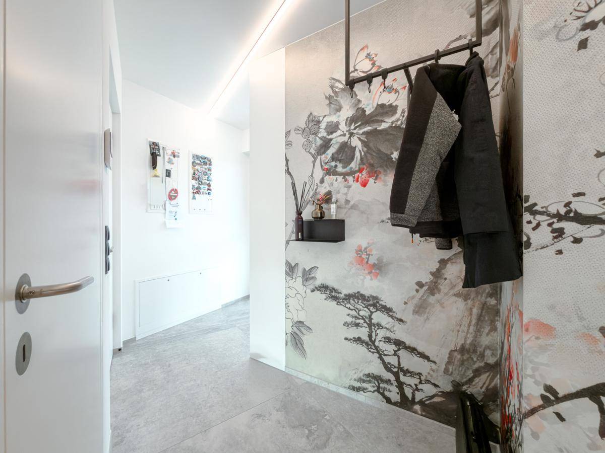 Eingangsbereich mit auffälliger floraler Tapete, praktischer Garderobe und hellem Fliesenboden.