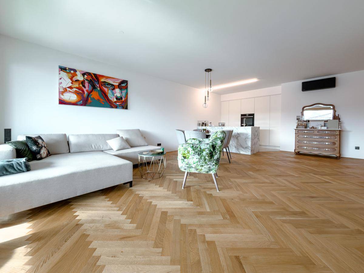 Geräumiger offener Wohnbereich mit bequemer Couch, farbenfrohem Kunstwerk und Blick auf die Küche.