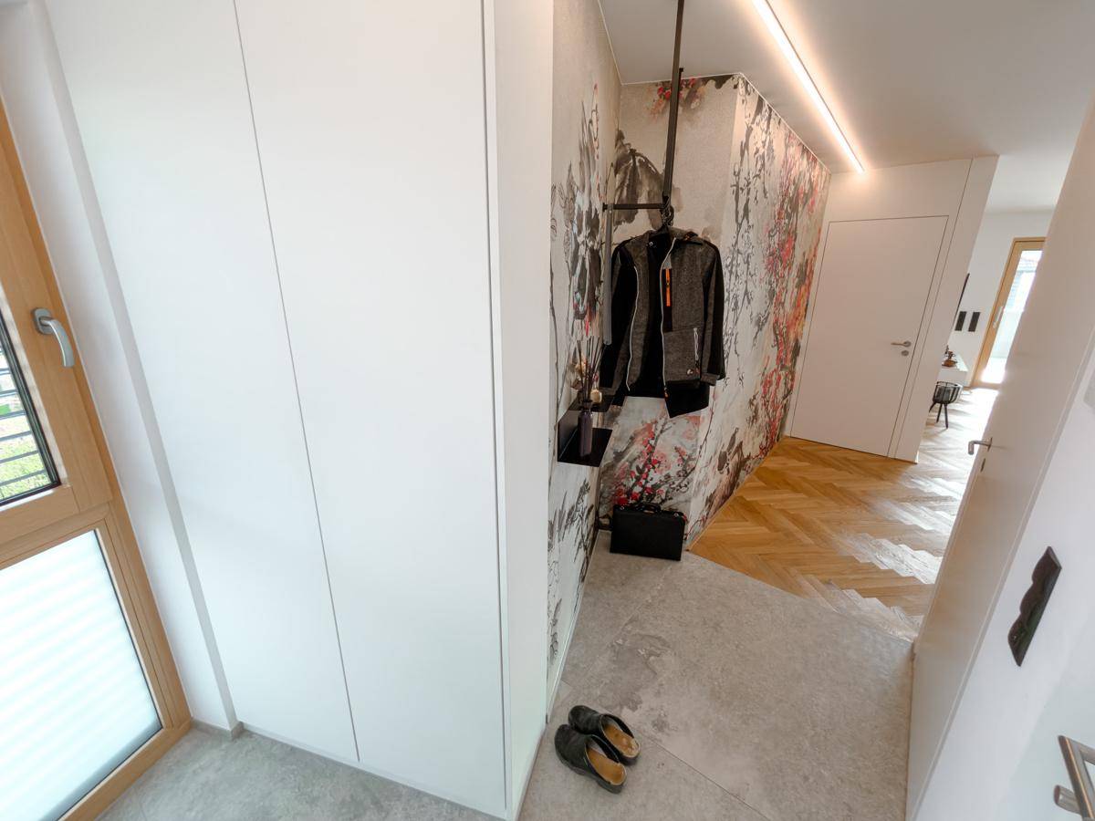 Heller Flur mit integrierten weißen Schränken, modernem Wanddesign und Fliesenboden.