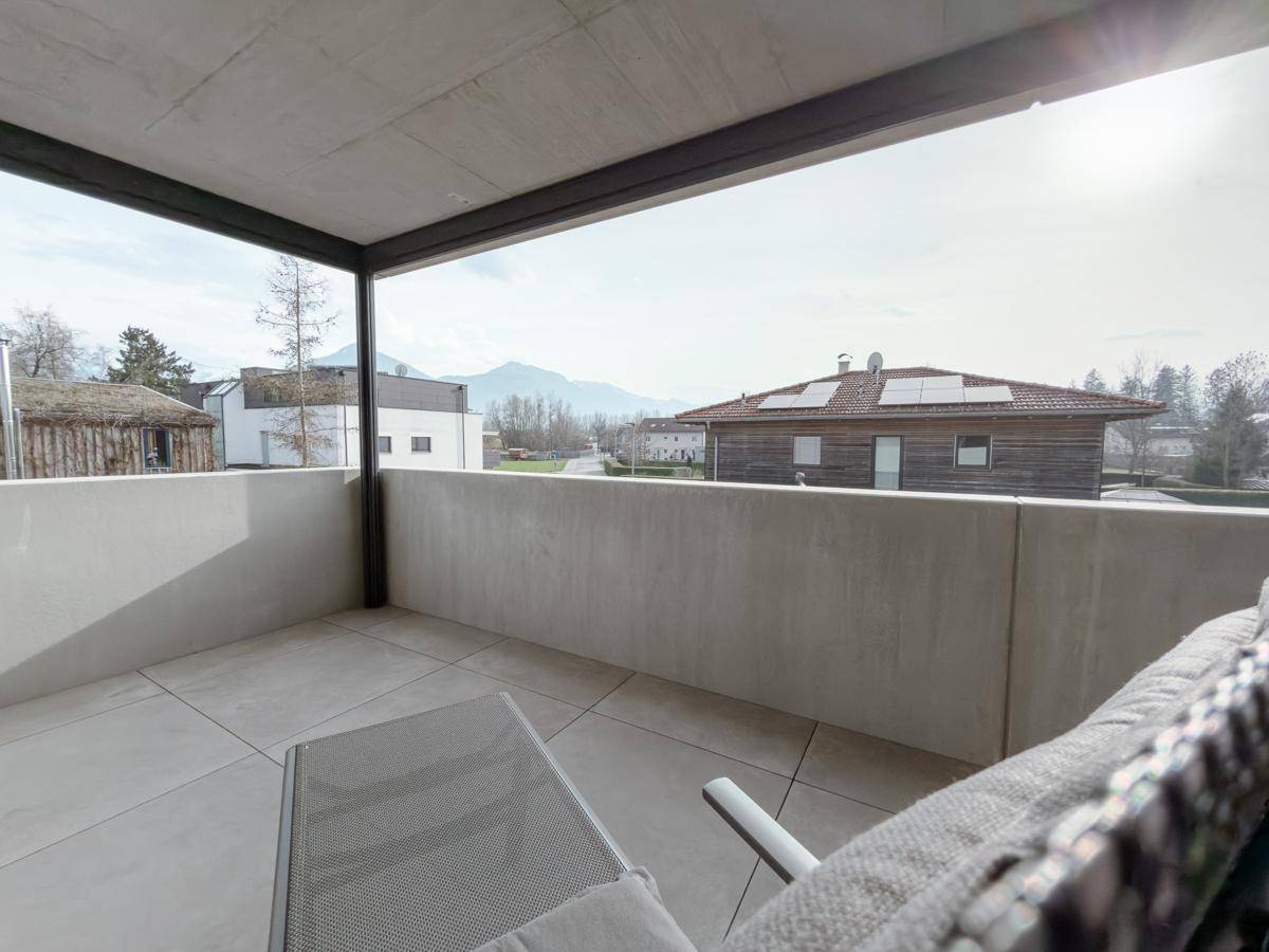 Blick von der Terrasse mit Betonbrüstung, Fliesenboden und weitem Ausblick auf die Berglandschaft.