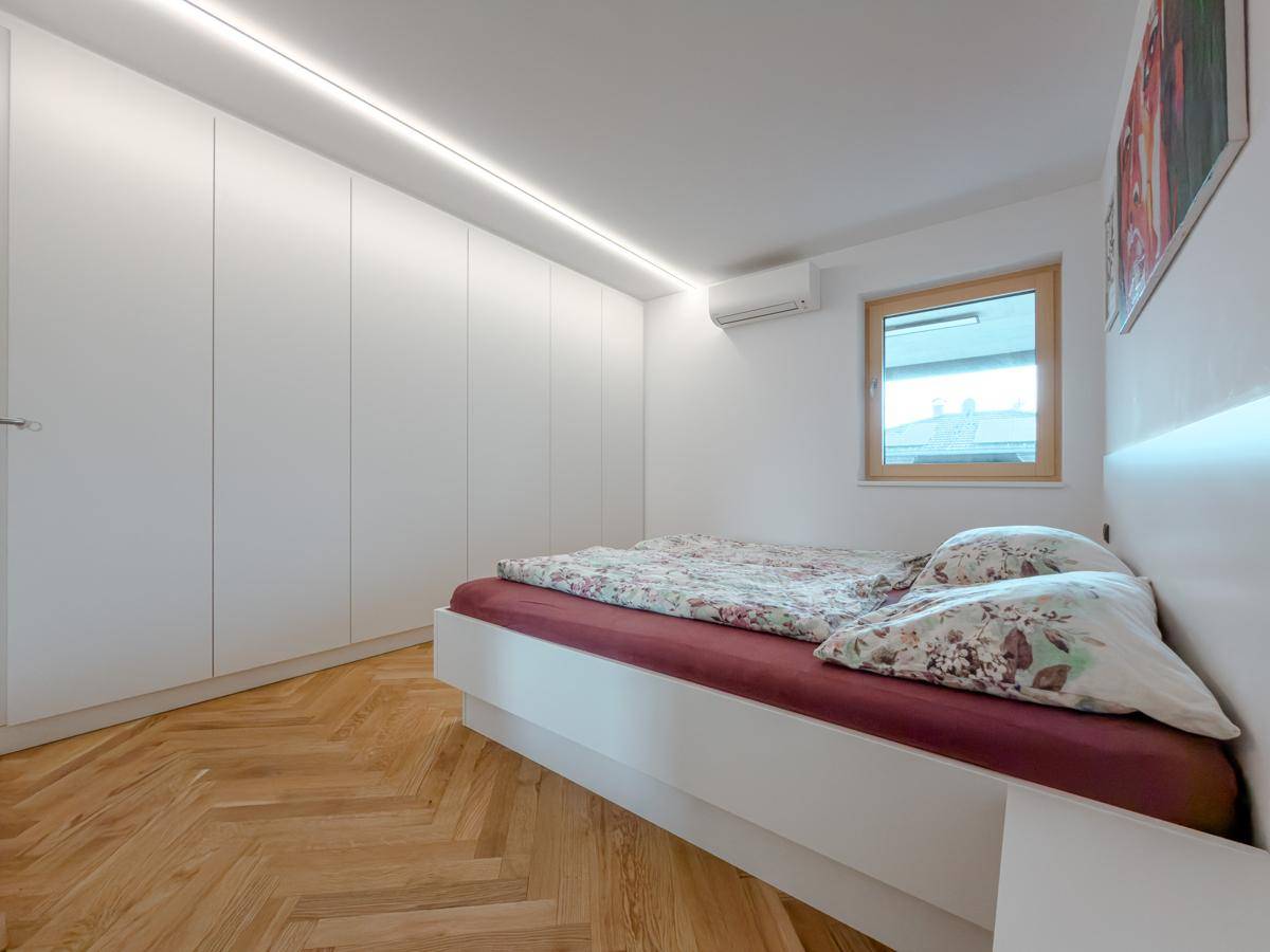 Helles Schlafzimmer mit integrierten weißen Kleiderschränken, Fischgrätparkett und Klimaanlage.