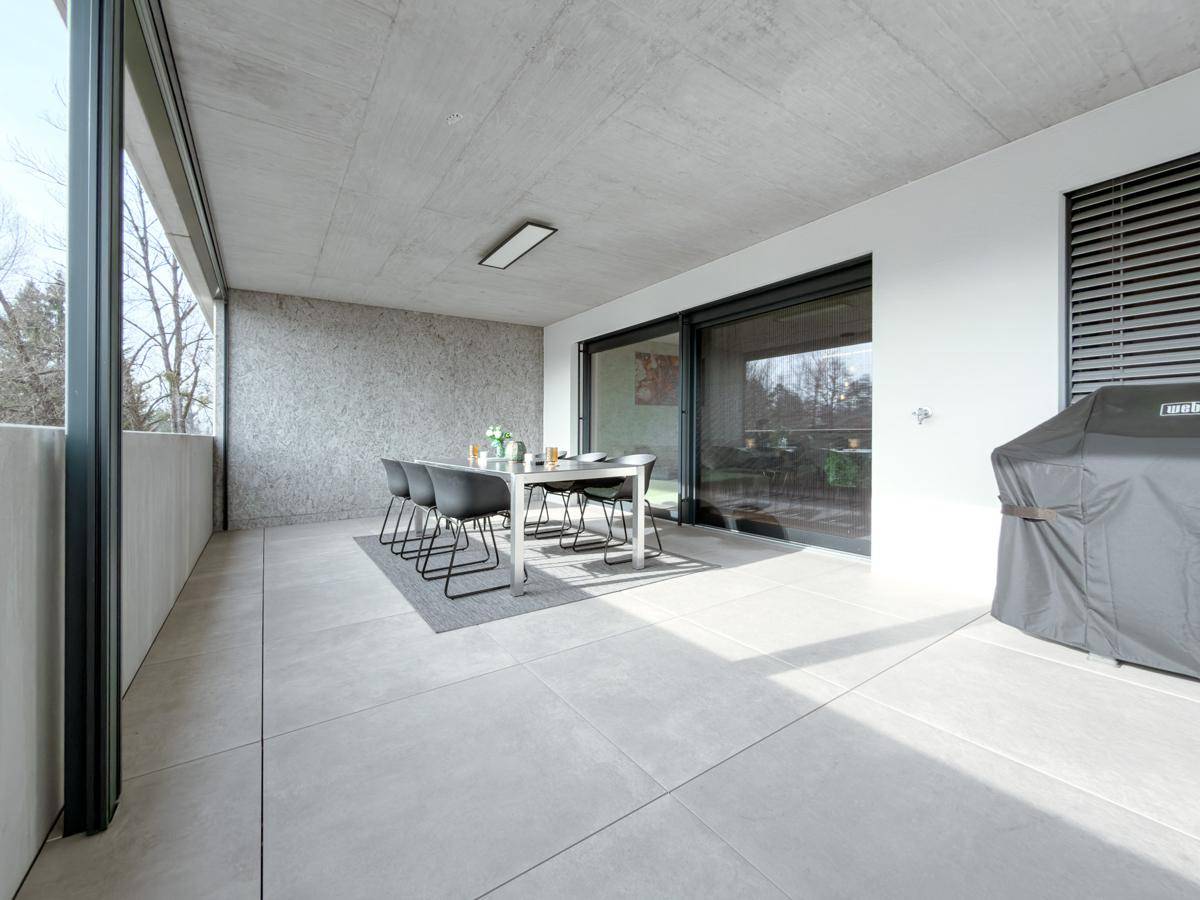 Weitläufige überdachte Terrasse mit Essbereich, Grill und Zugang zu den Innenräumen durch große Schiebetüren.