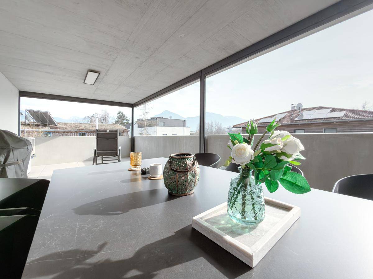 Detailansicht des Esstisches auf der Terrasse mit Dekoration und dem malerischen Bergblick.