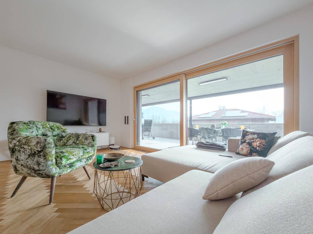 Gemütliches Wohnzimmer mit Fernseher, großem Fenster und direktem Zugang zur Terrasse mit Bergblick.