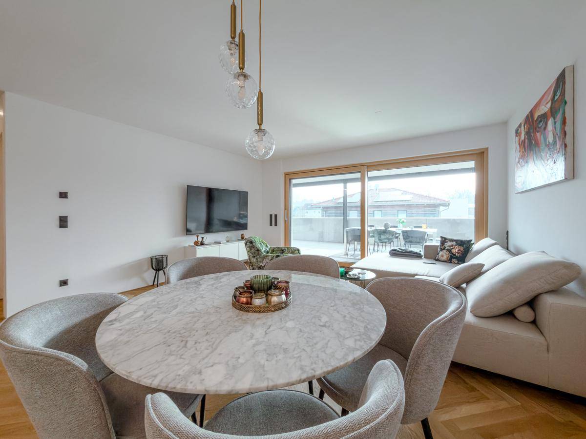 Eleganter Essbereich mit Marmortisch, modernen Stühlen und offenem Übergang zum Wohnzimmer.