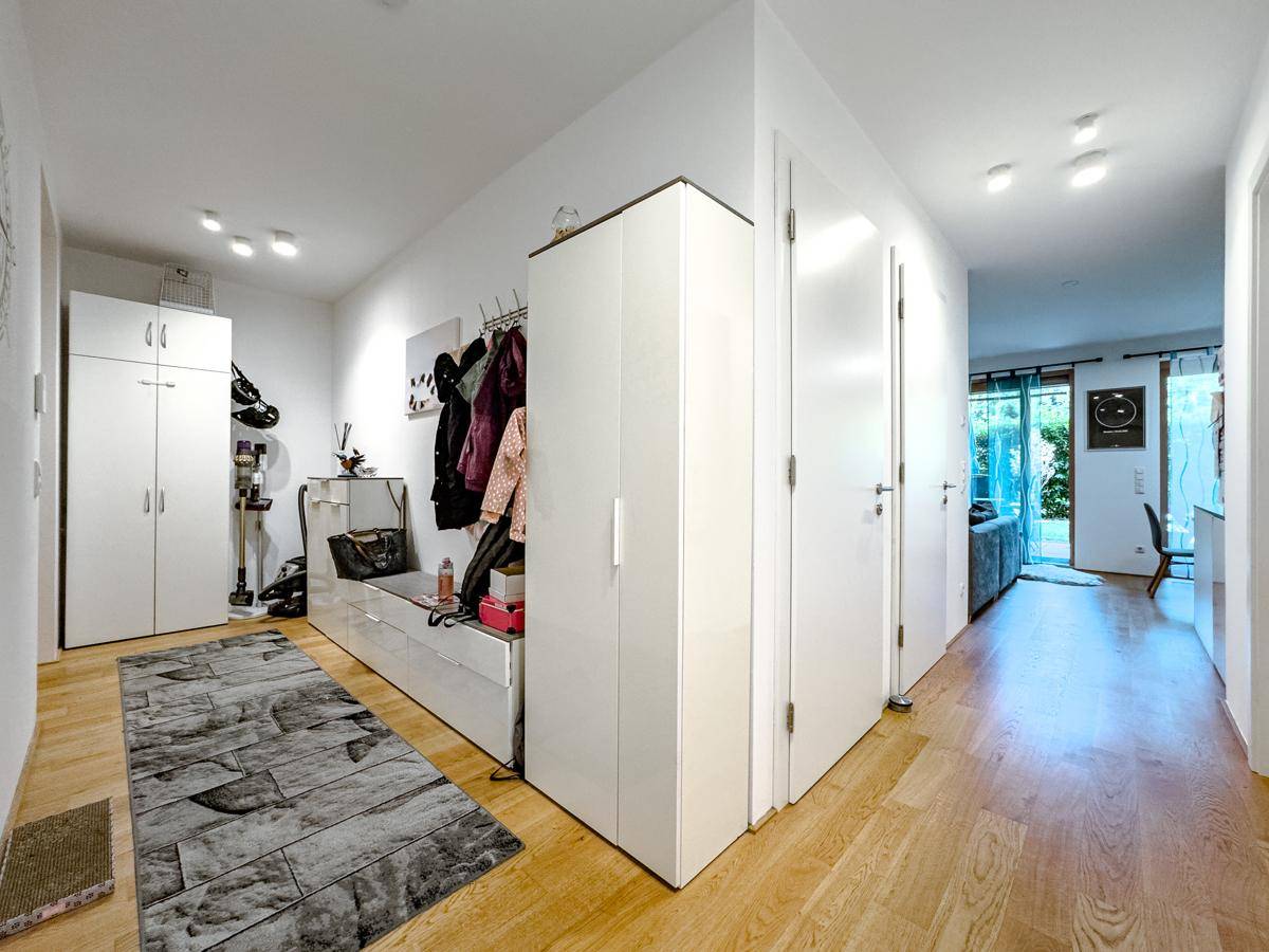 Heller Flur mit Holzfußboden, praktischer Garderobe und Zugang zu weiteren Räumen, gut beleuchtet.