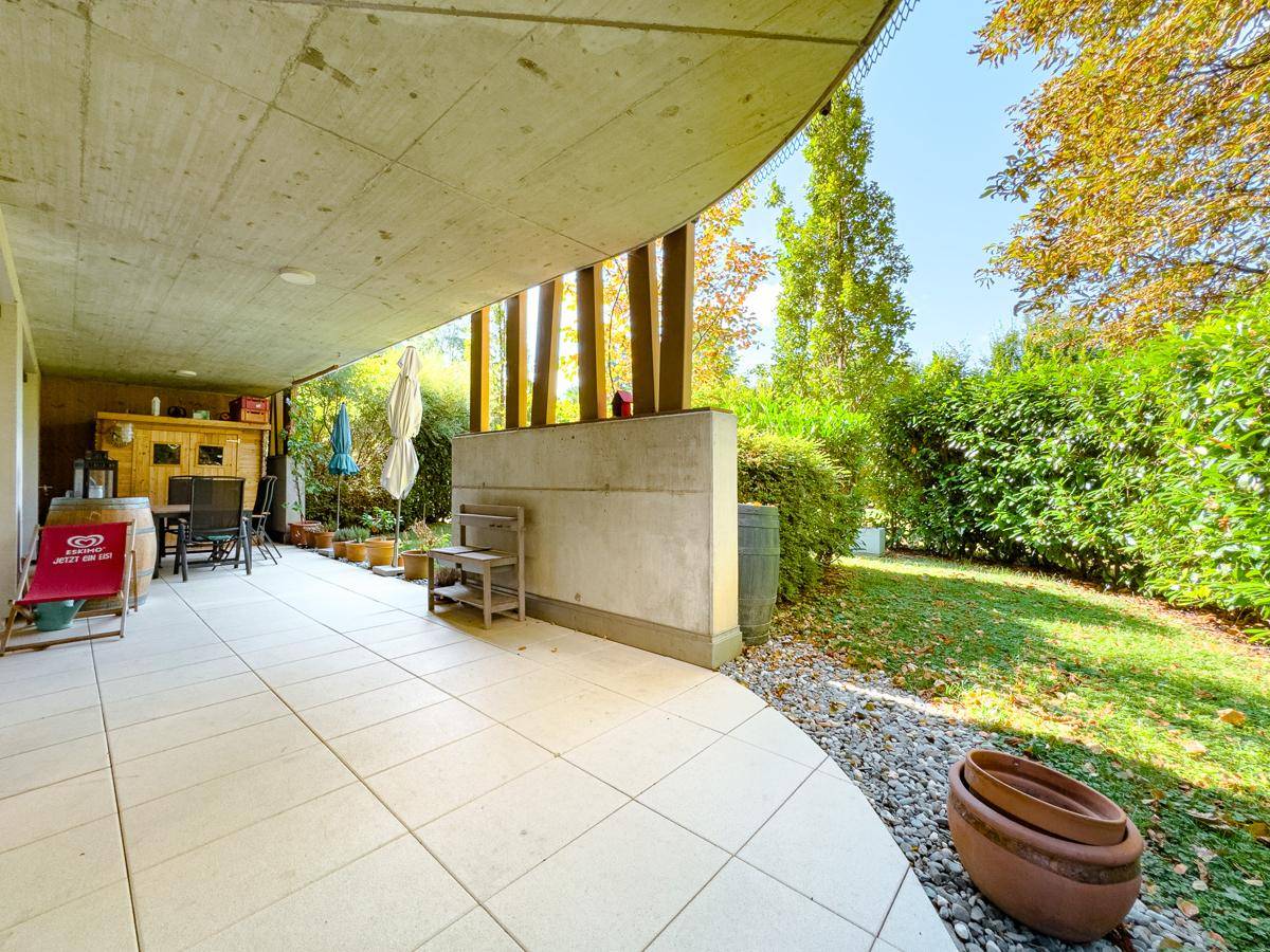 Weitläufige geflieste Terrasse mit Zugang zum Garten und umgebender Bepflanzung.