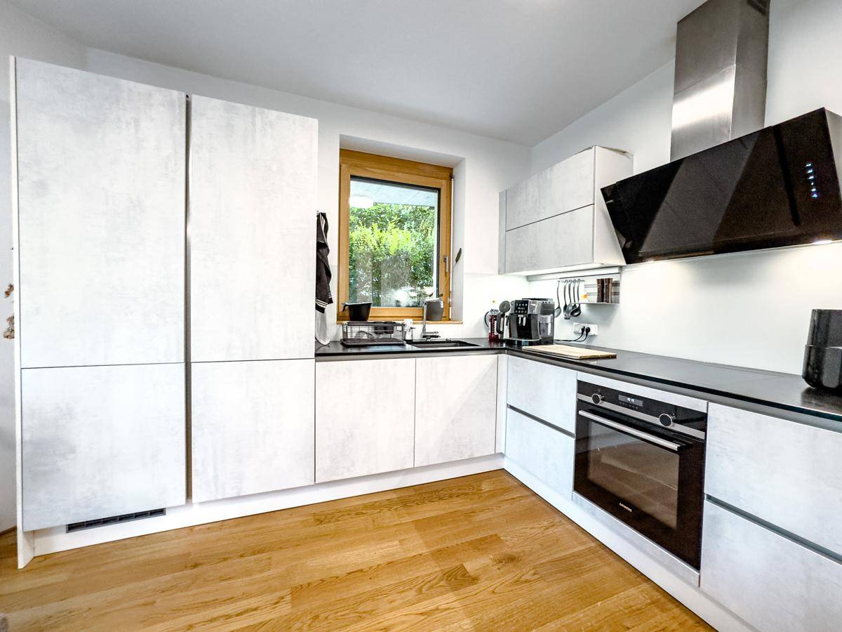 Helle, moderne Küche mit integrierten Geräten, Fenster und Holzfußboden, funktional und stilvoll.
