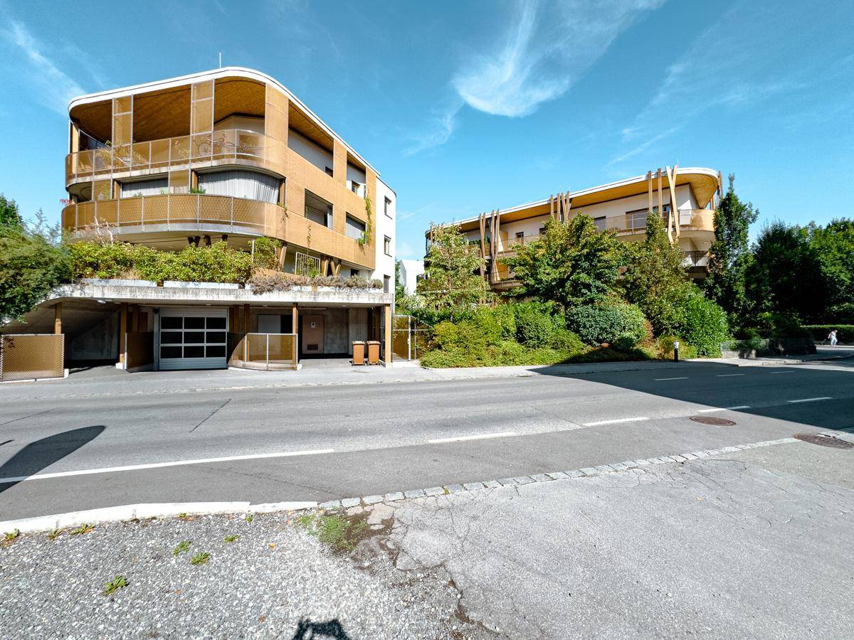 Moderne Wohnanlage mit Tiefgaragenzufahrt und ansprechender Architektur in grüner Umgebung.