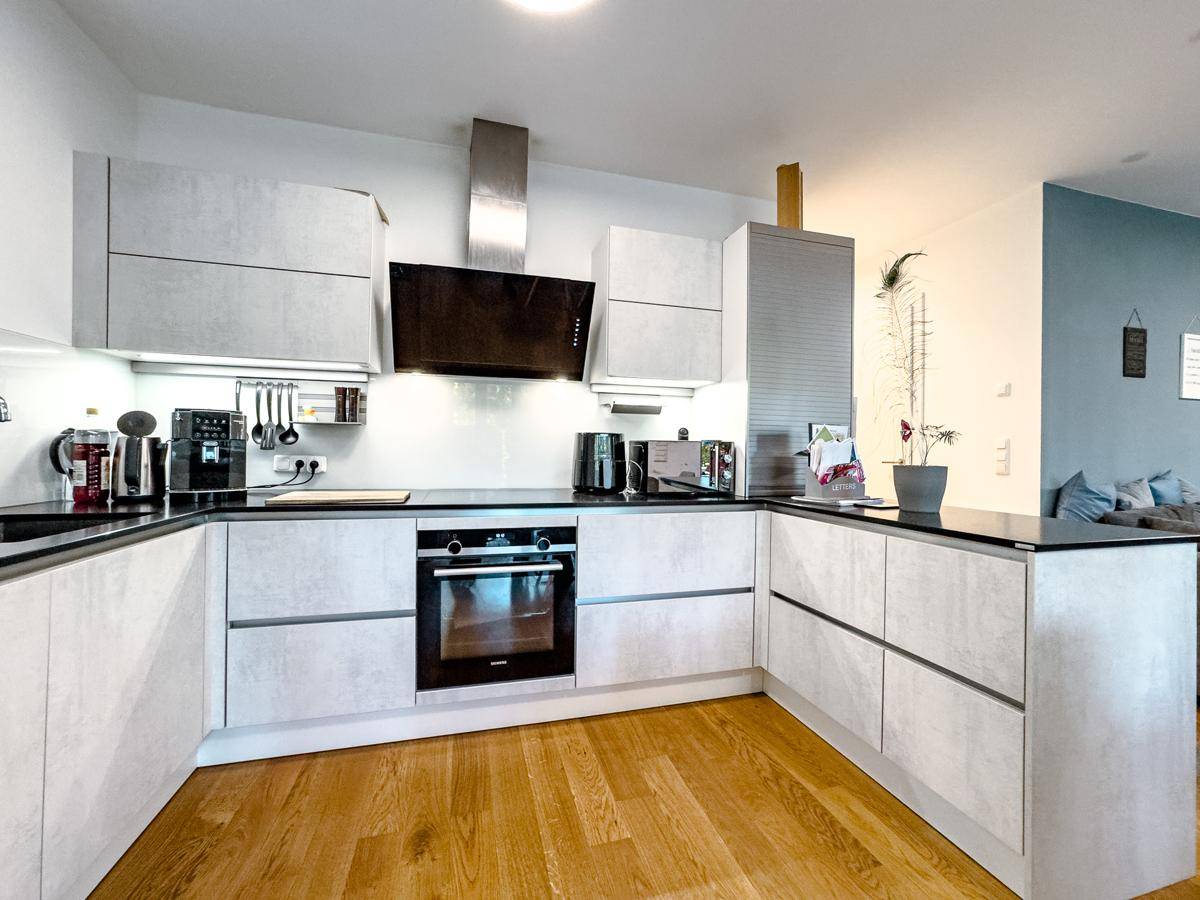 Gut ausgestattete moderne Küche mit Backofen, Dunstabzugshaube und viel Arbeitsfläche.