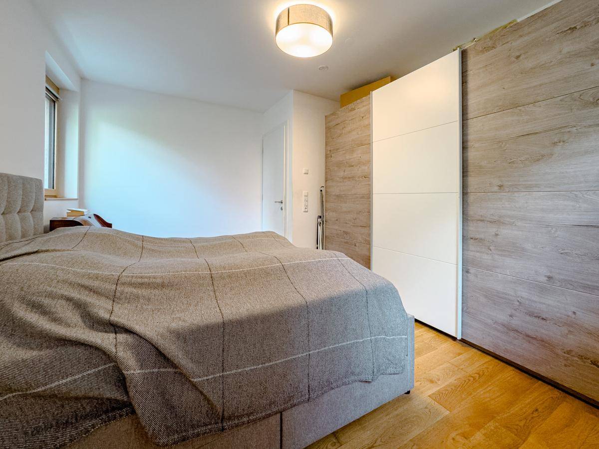 Schlafzimmer mit Doppelbett, Holzfußboden und großem Kleiderschrank, hell und einladend gestaltet.