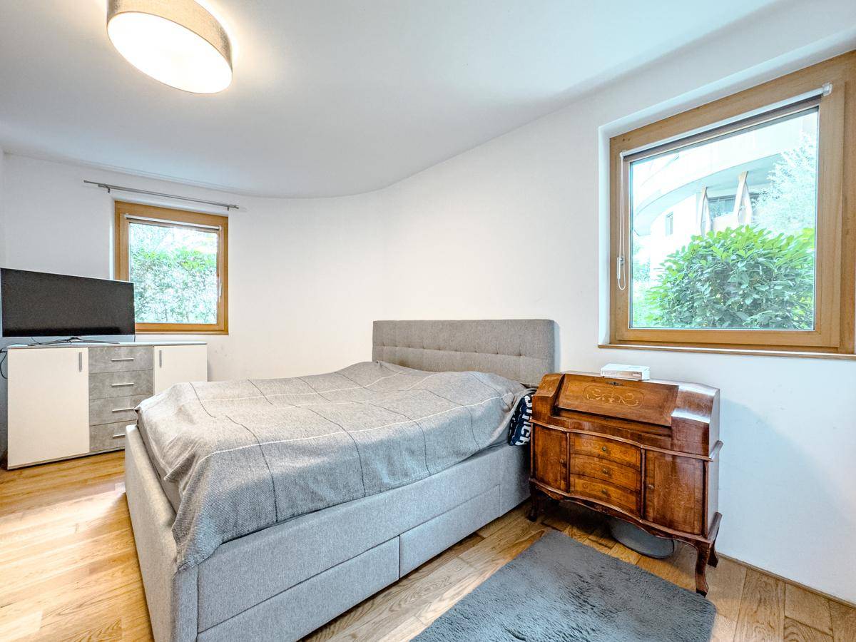 Gemütliches Schlafzimmer mit Doppelbett, Holzfußboden und Blick ins Grüne durch das Fenster.