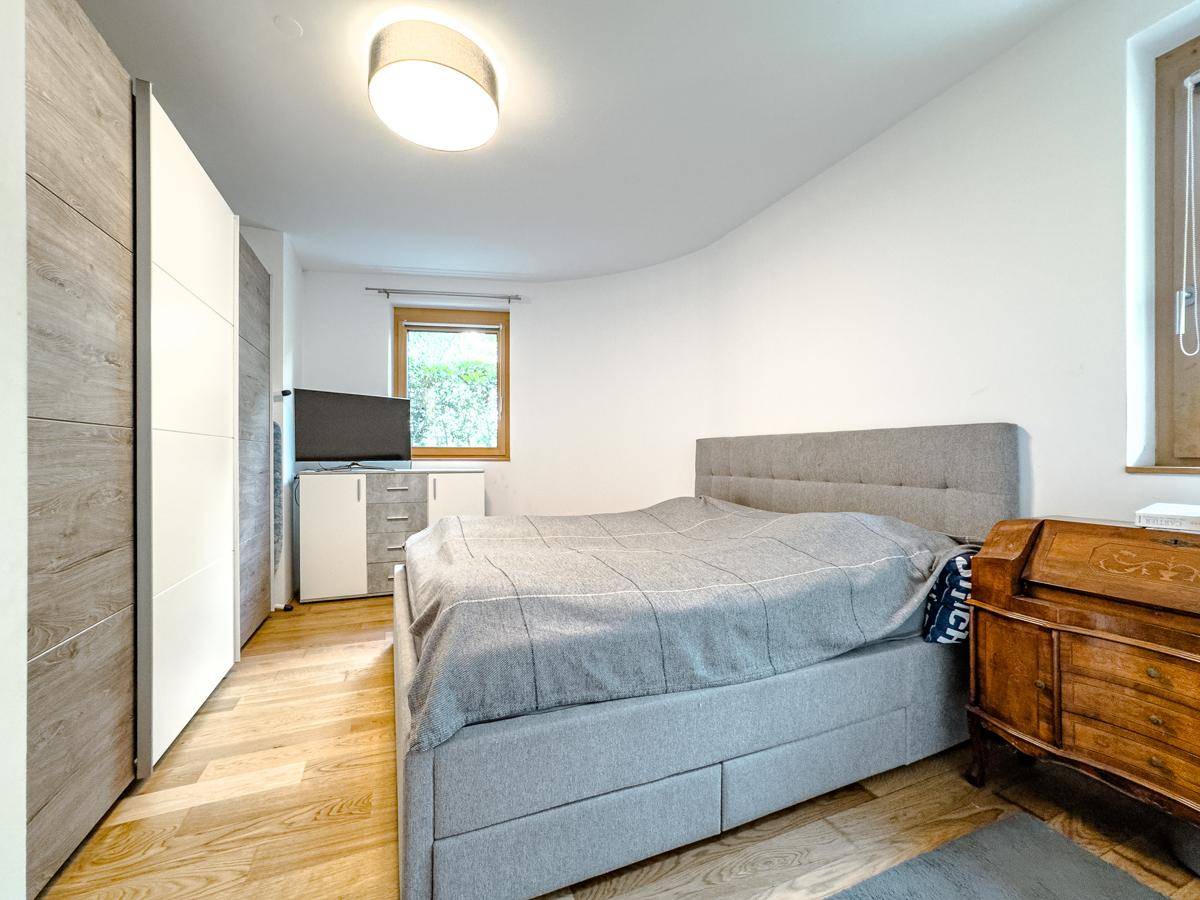 Gemütliches Schlafzimmer mit Doppelbett, Holzfußboden und modernem Kleiderschrank, mit natürlichem Licht.