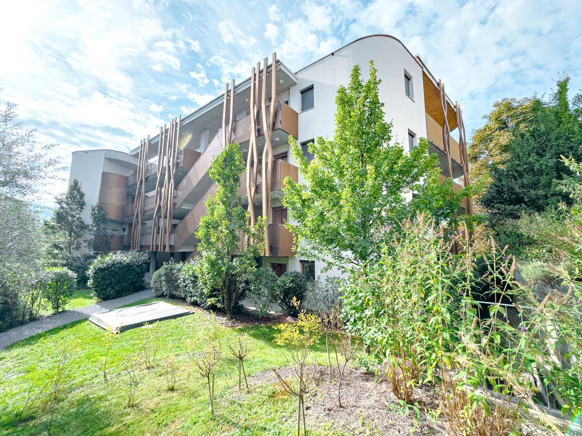 Rückansicht des modernen Wohngebäudes mit üppiger Bepflanzung und gepflegtem Gartenbereich.
