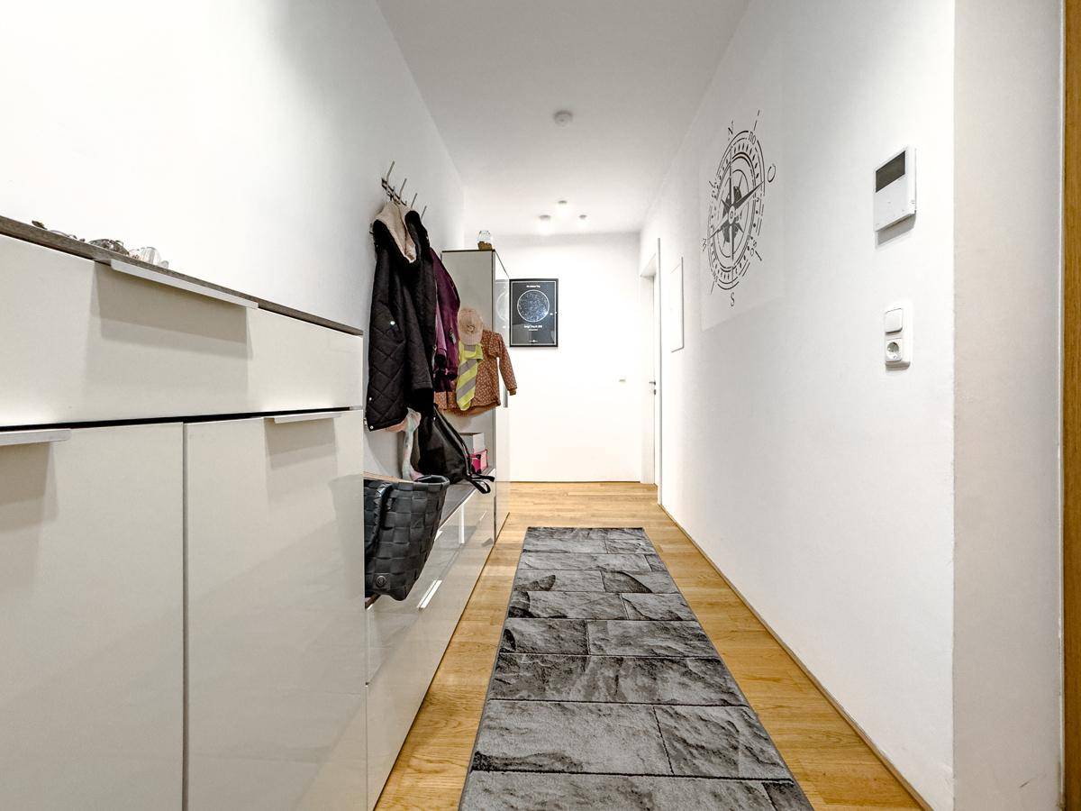 Geräumiger Flur mit Holzfußboden, Garderobe und dekorativer Wandgestaltung, praktisch und hell.