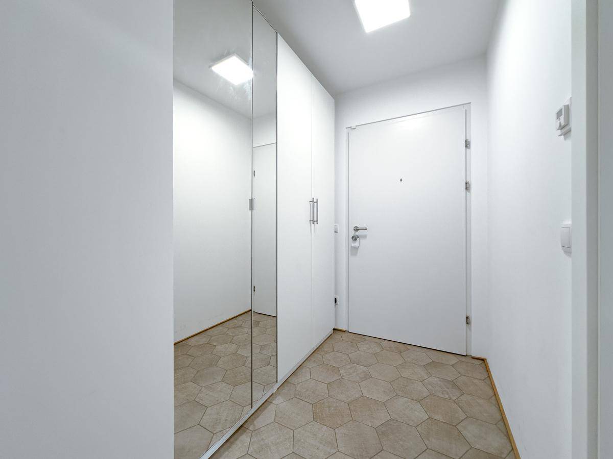 Eingangsbereich mit modernen sechseckigen Fliesen und einem Spiegelschrank, der viel Stauraum bietet.