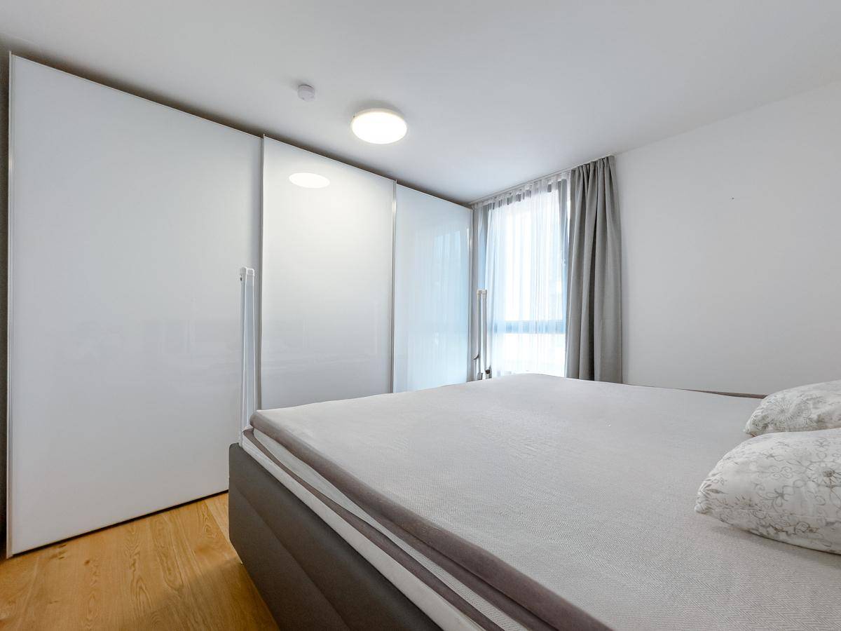 Helles Schlafzimmer mit großem Kleiderschrank und Holzboden, bietet direkten Zugang zum Balkon.
