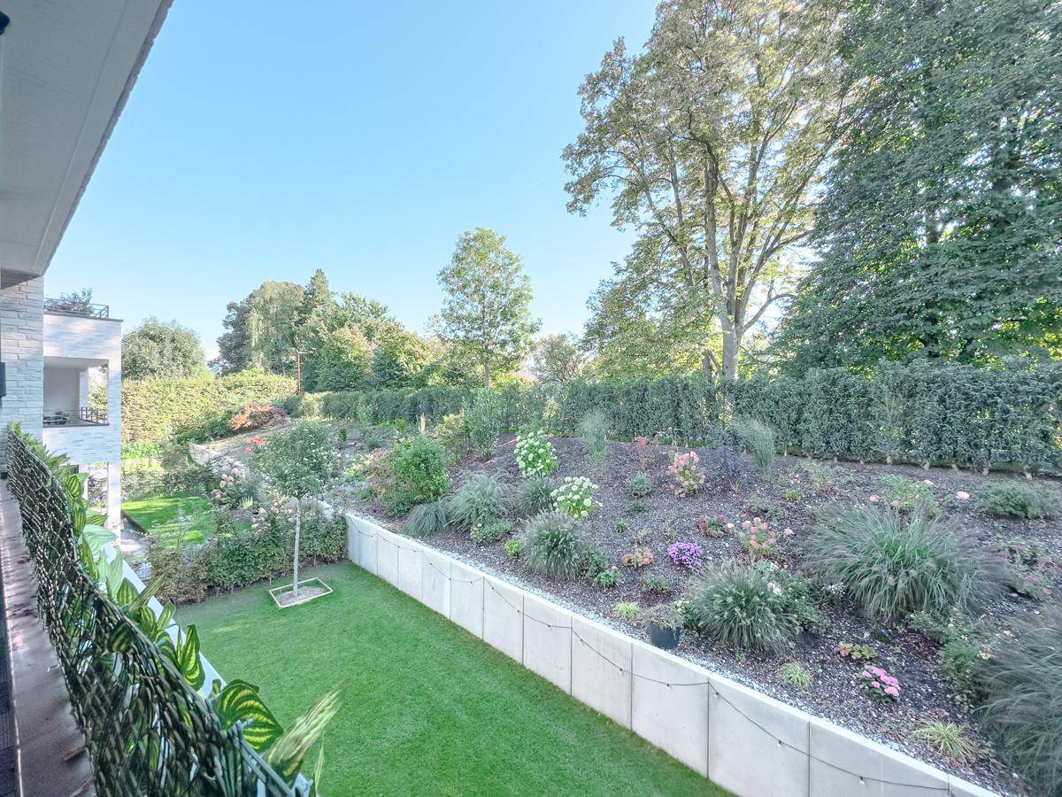 Gepflegter Gartenbereich mit Rasenfläche und Blumenbeeten, bietet eine ruhige grüne Umgebung.