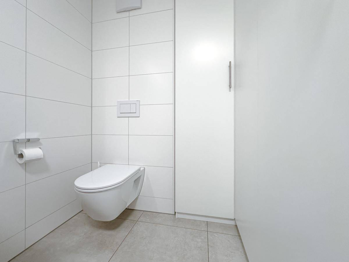 Separates WC mit wandhängender Toilette und modernen Fliesen, sehr sauber und funktional.