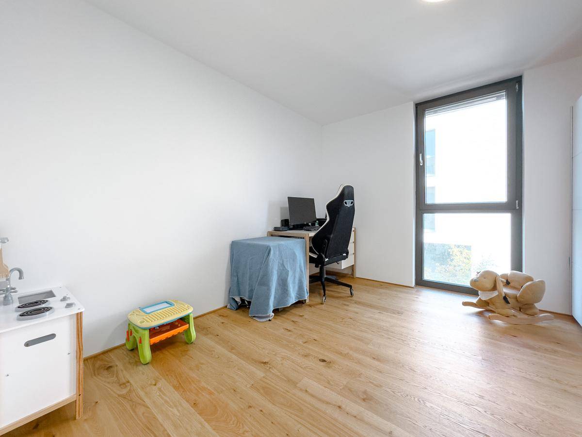 Vielseitig nutzbarer Raum mit Holzboden und großem Fenster, ideal als Büro oder Kinderzimmer.