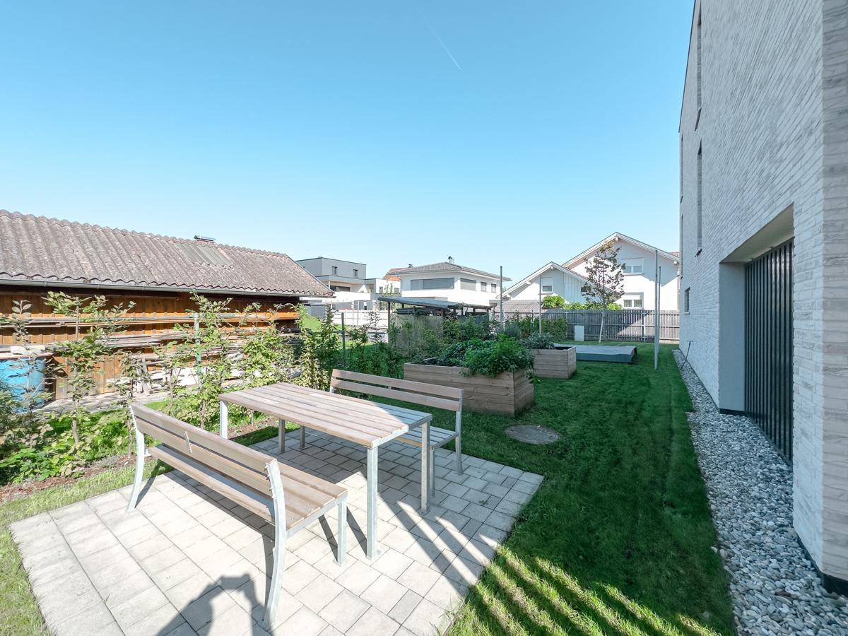Gemeinschaftlicher Gartenbereich mit Sitzgelegenheiten und Hochbeeten, ideal für entspannte Stunden.