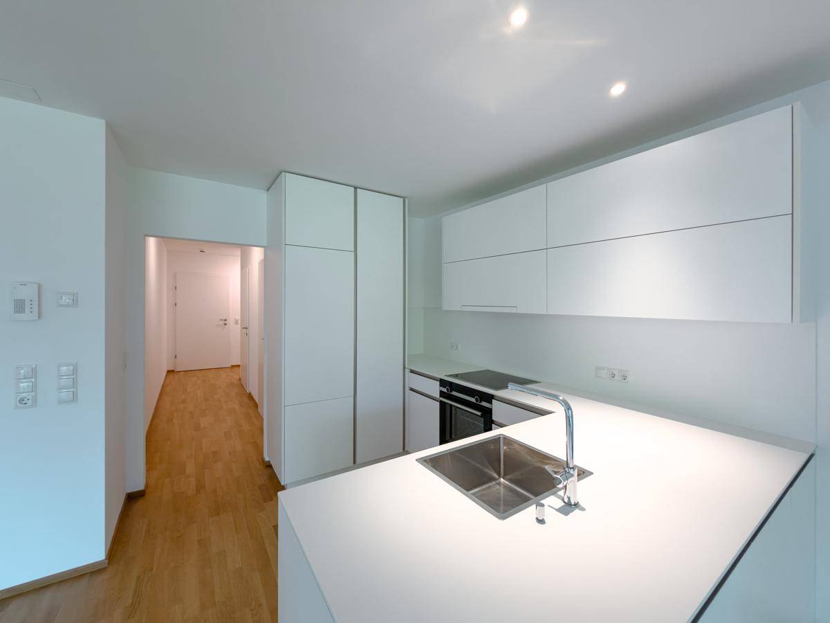 Moderne Einbauküche mit weißen Schränken, Spüle und integrierten Geräten.