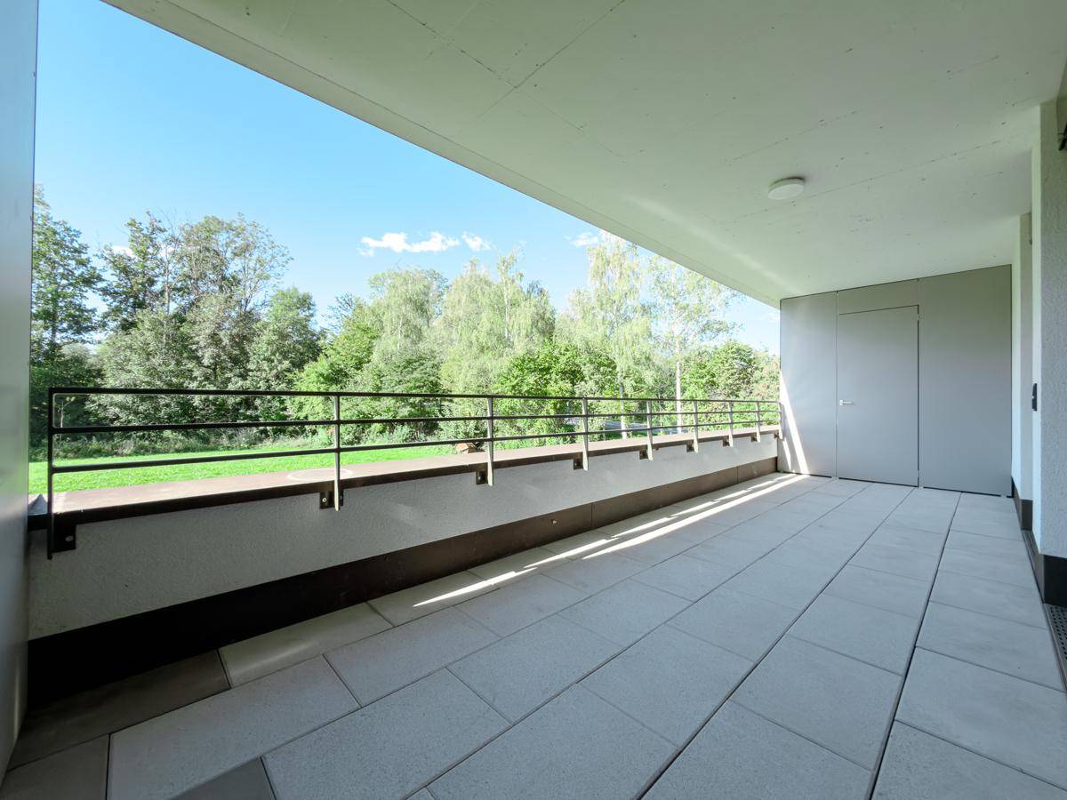 Überdachter Balkon mit Fliesenboden und Blick auf die umliegende Natur.