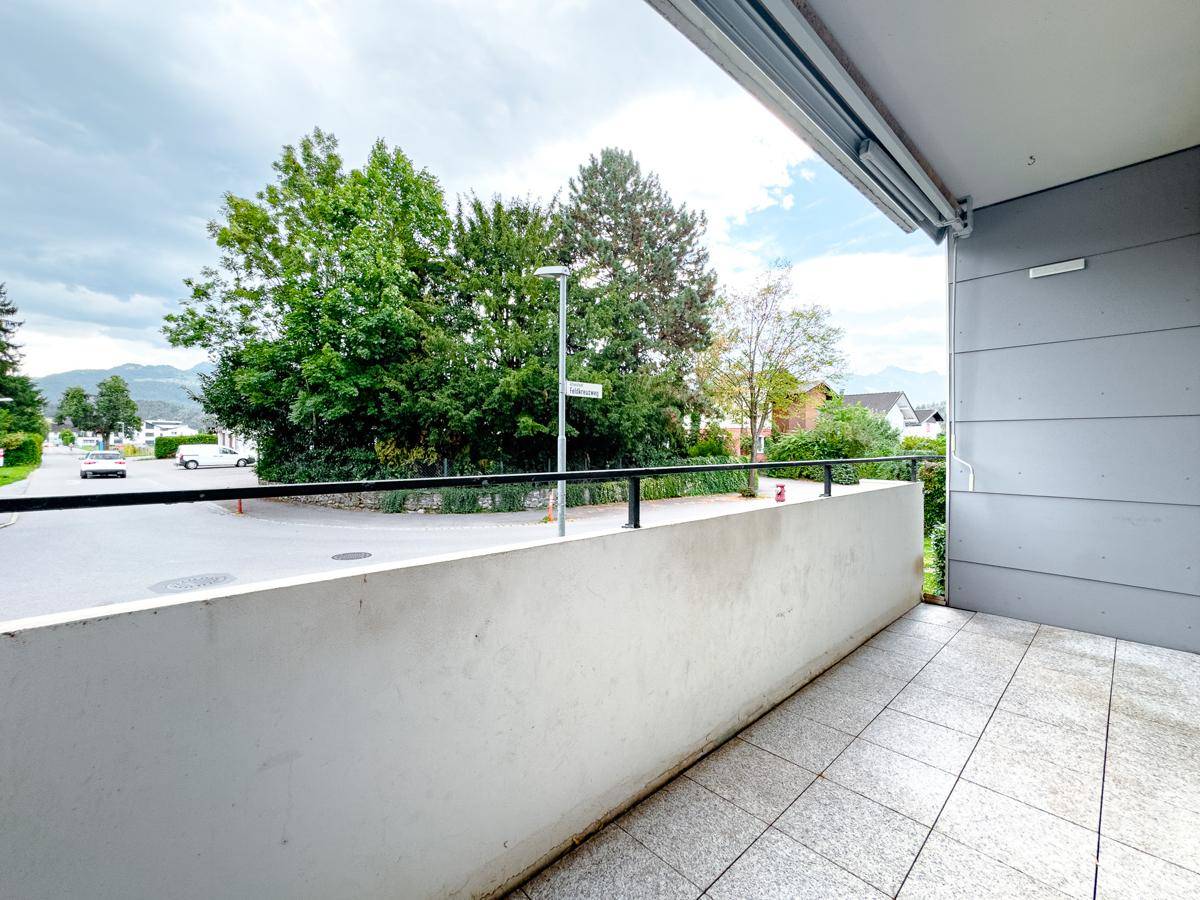 Geräumiger Balkon mit Fliesenboden und Blick auf die Straße und die umliegende grüne Landschaft.