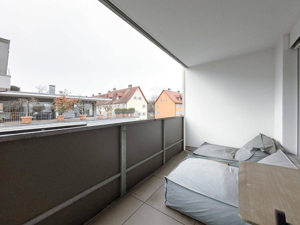 Balkon mit Fliesenboden, Sitzsäcken und Blick auf die umliegenden Gebäude.