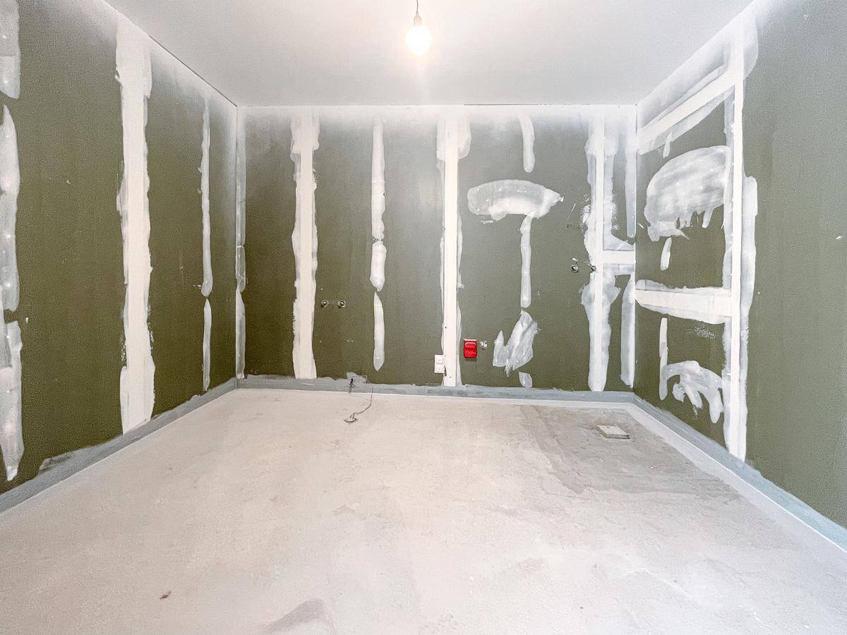 Badezimmer im Rohbau mit grünen Gipskartonwänden, vorbereitet für Fliesen und Installationen.