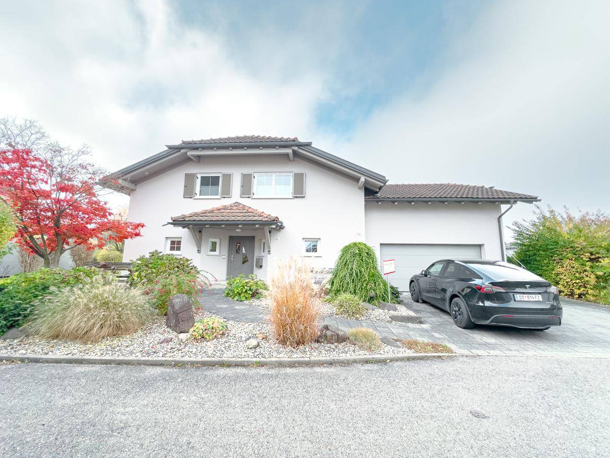 Ansicht des Einfamilienhauses mit Garage, gepflasterter Einfahrt und Vorgarten.