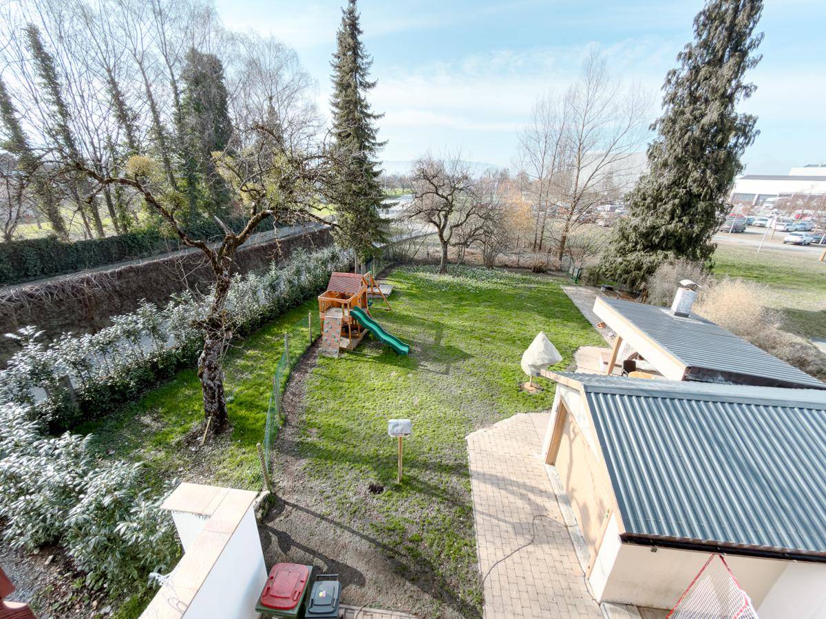 Überblick über den großen Garten mit Spielplatz, Rasenfläche und angrenzendem Gebäude.