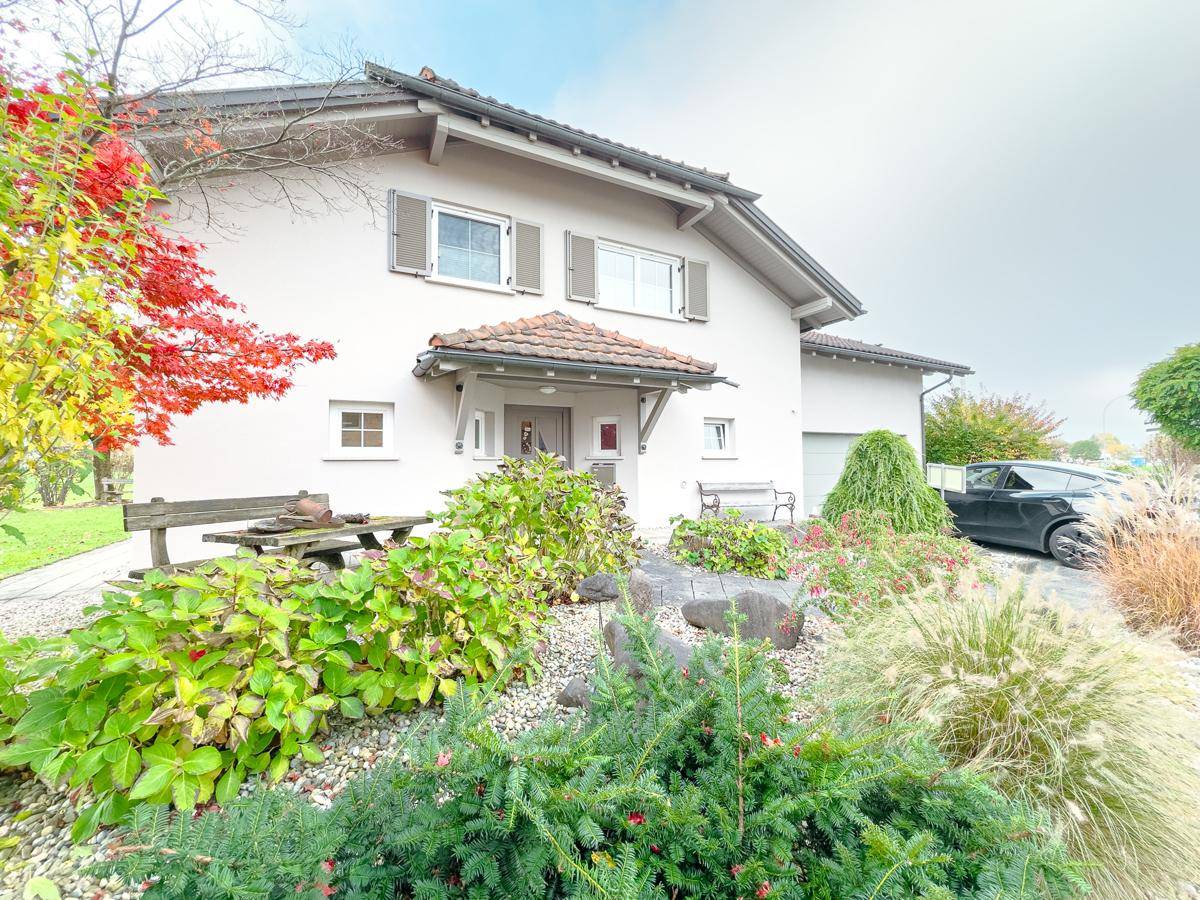 Vorderansicht des Hauses mit gepflegtem Vorgarten, Eingangsbereich und Garagenzufahrt.