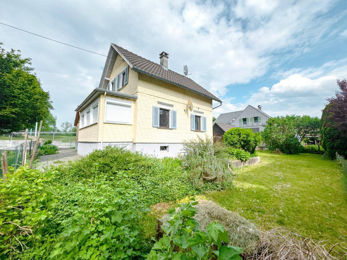 Seitenansicht des Hauses mit üppigem Grün, Gartenbereich und Blick auf die Umgebung.