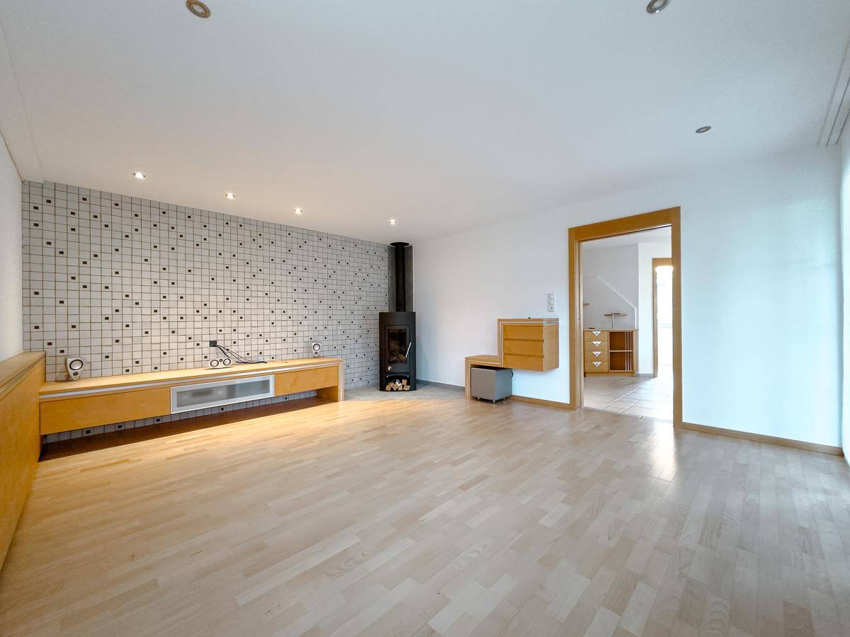 Geräumiges Wohnzimmer mit Kaminofen, Holzboden und moderner Wandgestaltung.
