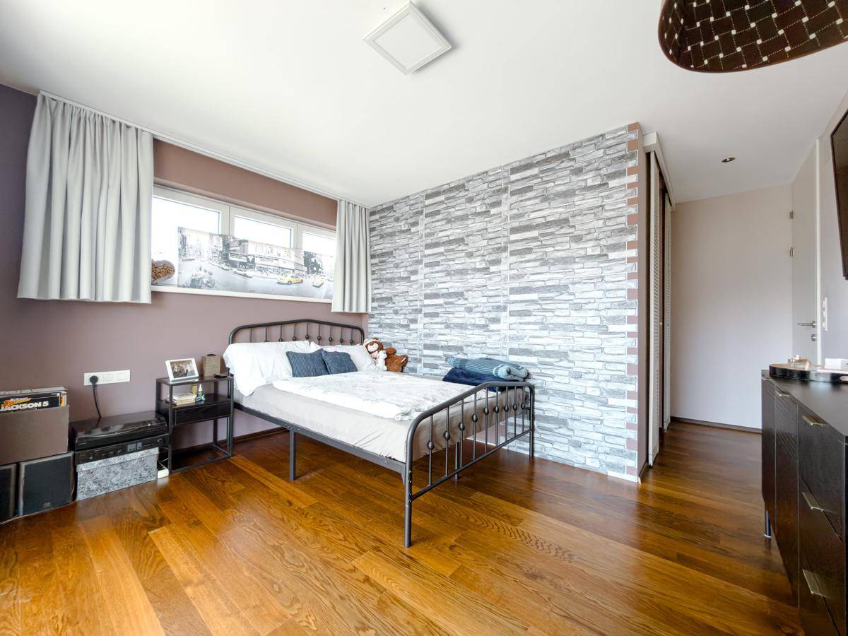Schlafzimmer mit Holzboden, Steinwandakzent und Doppelbett, bietet eine moderne Atmosphäre.