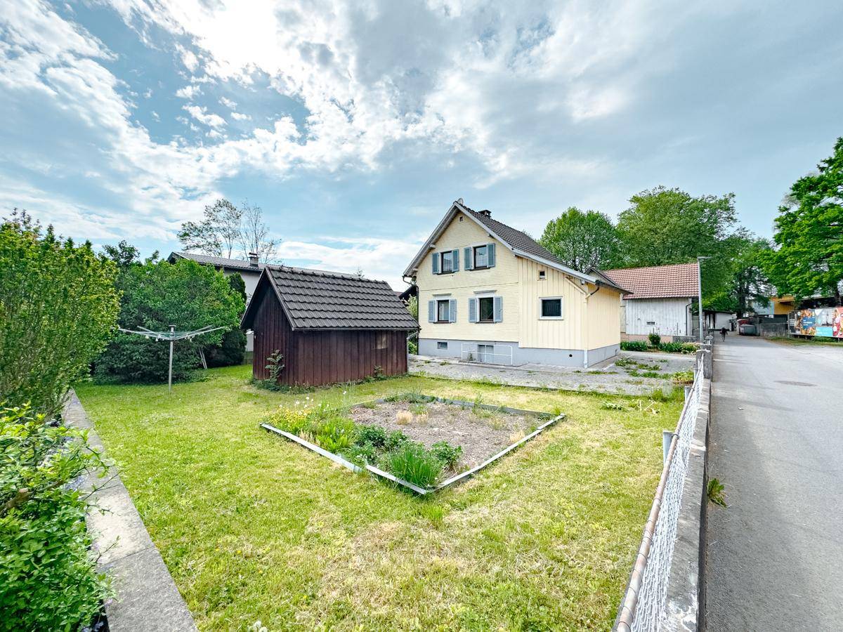 Gepflegter Gartenbereich mit Rasenfläche, Hochbeet und Blick auf die ruhige Wohngegend.