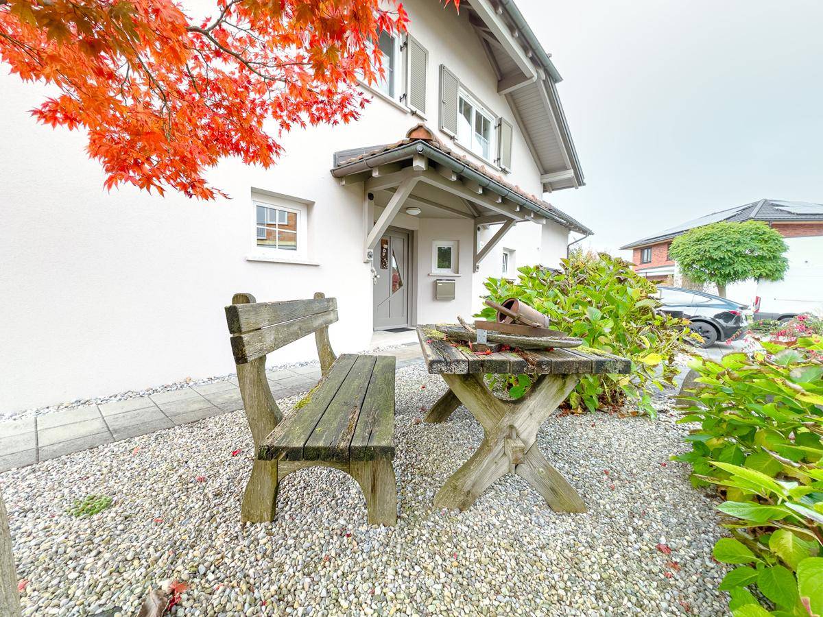 Detailansicht des Hauseingangs mit kleiner Sitzbank und dekorativen Kiesbeeten.