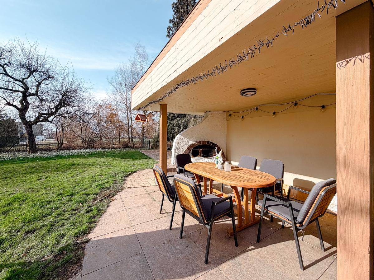 Überdachte Terrasse mit Esstisch und Stühlen, ideal für Mahlzeiten im Freien und Entspannung.
