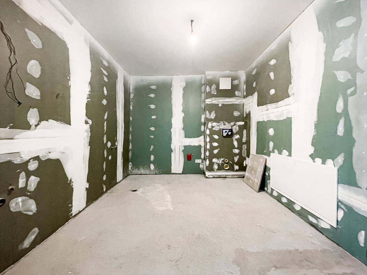 Badezimmer im Rohbau mit vorbereiteten Wänden für Fliesen und sichtbaren Installationen.