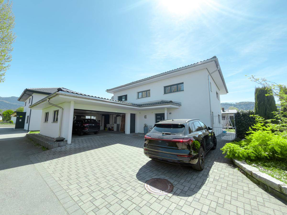 Vorderansicht des modernen Hauses mit gepflasterter Auffahrt und Carport.