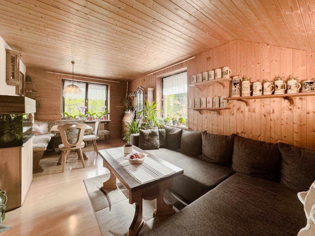 Rustikaler Wohn-Essbereich mit Holztäfelung, gemütlichem Sofa und traditionellem Essplatz.