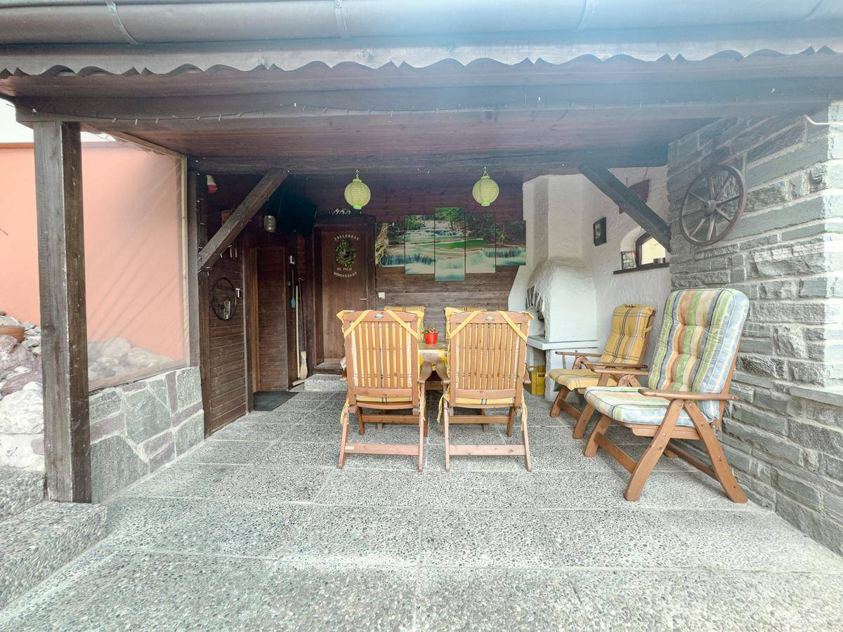Gemütliche überdachte Terrasse mit Steinwänden und Gartenmöbeln, perfekt für entspannte Stunden.