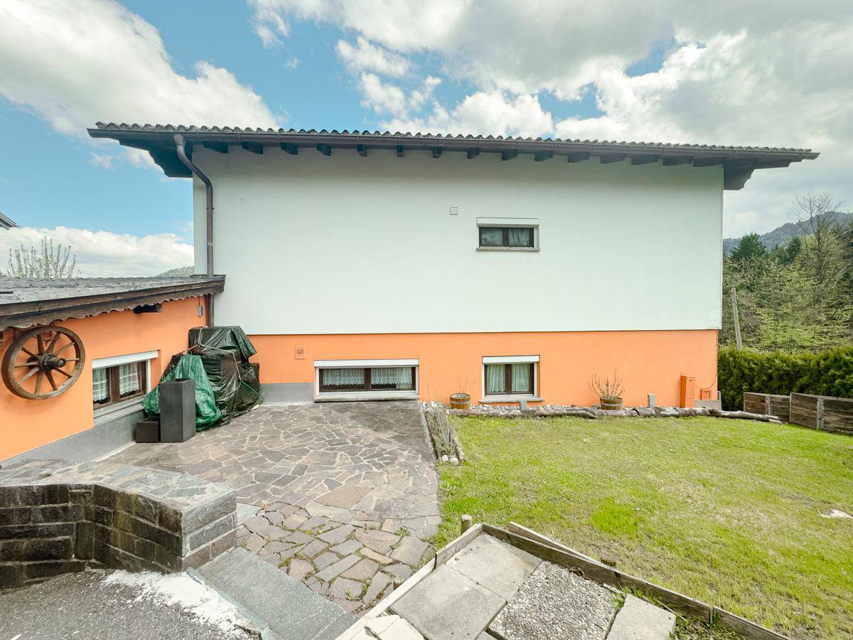 Hinterer Bereich des Hauses mit Rasenfläche, gepflastertem Weg und Blick ins Grüne.