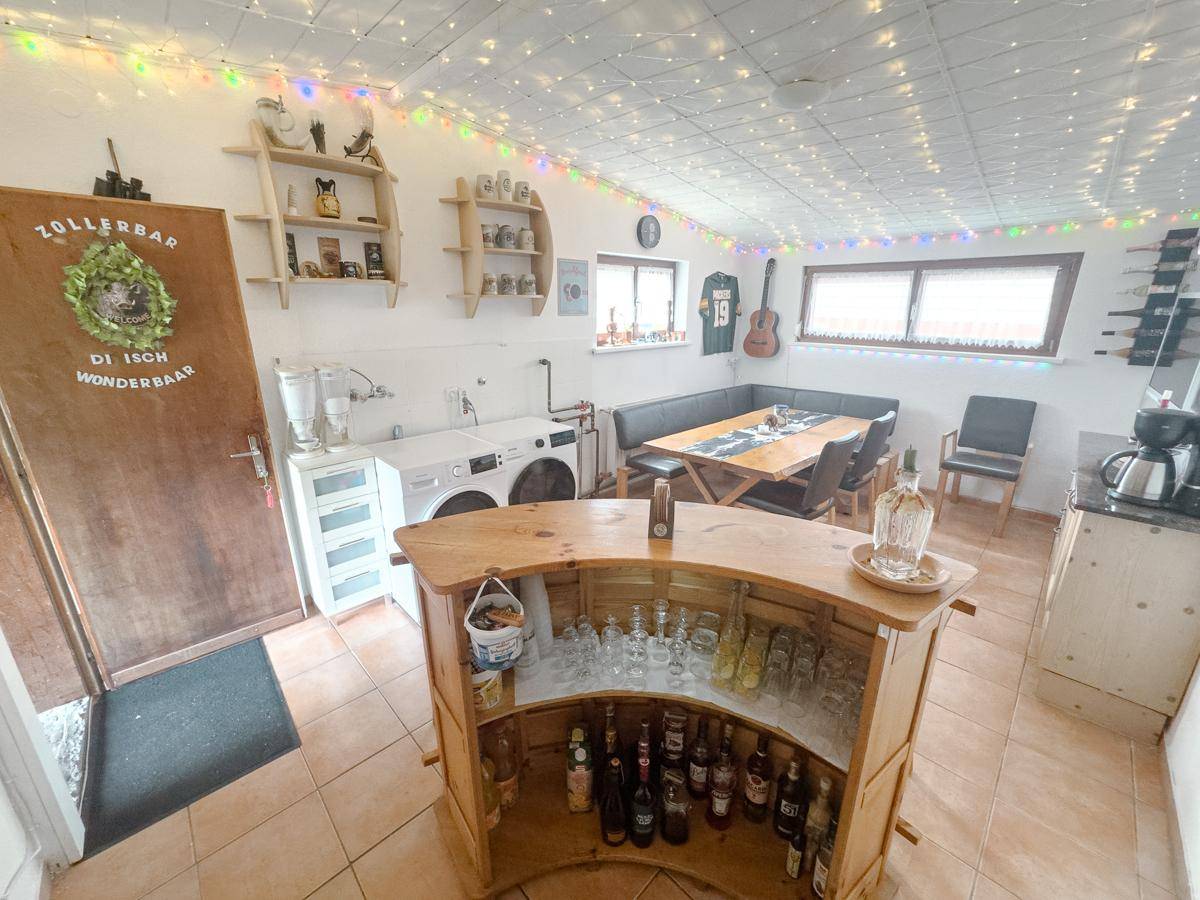 Geräumiger Mehrzweckraum mit Bar, Essbereich und Waschmaschine, ideal für gesellige Abende.
